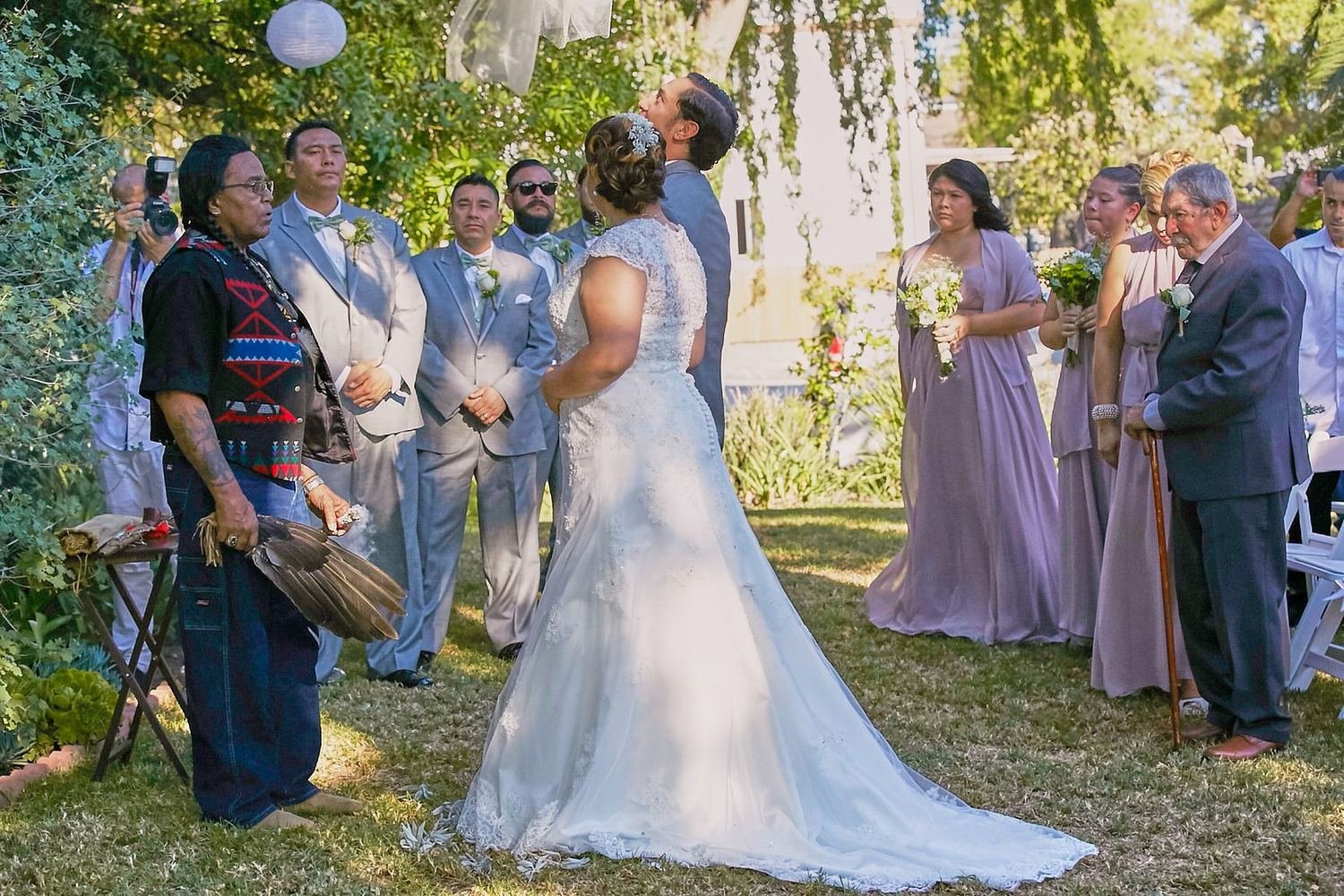 Outdoor Los Angeles wedding ceremony as the couple kisses beneath a floral arch